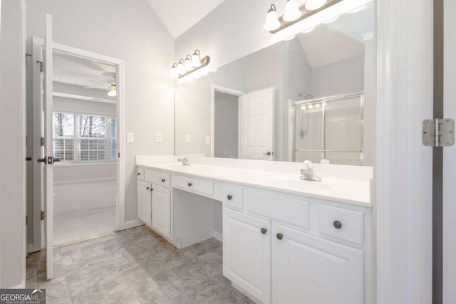 bathroom with a stall shower, a sink, double vanity, lofted ceiling, and ceiling fan