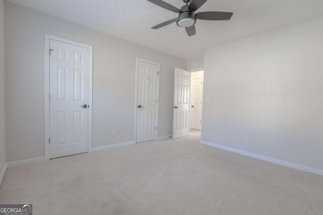 unfurnished bedroom with baseboards, light colored carpet, and ceiling fan