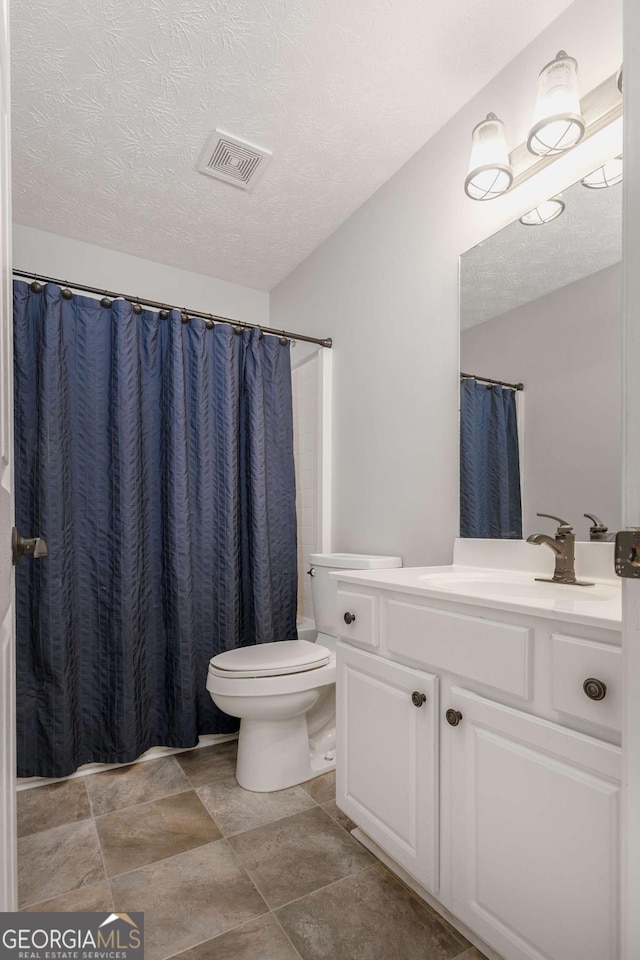 full bath featuring visible vents, curtained shower, toilet, vanity, and a textured ceiling