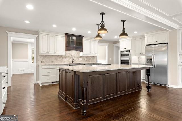 kitchen with a sink, stainless steel appliances, a kitchen island, and white cabinets