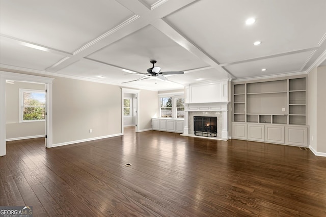 unfurnished living room with coffered ceiling, a healthy amount of sunlight, a fireplace, and dark wood-style flooring