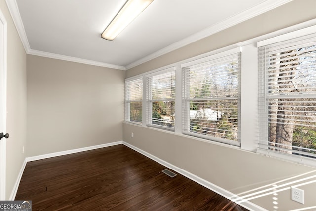 empty room featuring visible vents, baseboards, dark wood finished floors, and crown molding