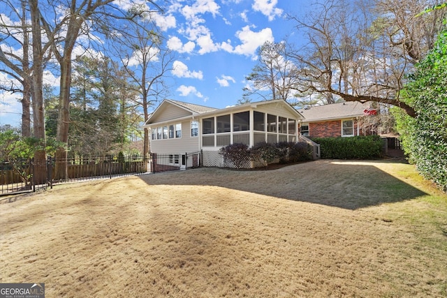 view of front of property featuring a front yard, fence, brick siding, and a sunroom