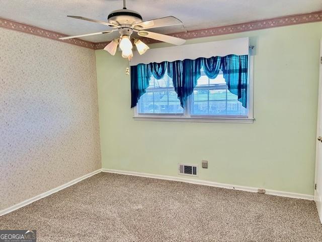 spare room featuring visible vents, baseboards, ceiling fan, and carpet flooring