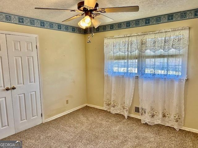 unfurnished room featuring baseboards, a textured ceiling, ceiling fan, and carpet flooring