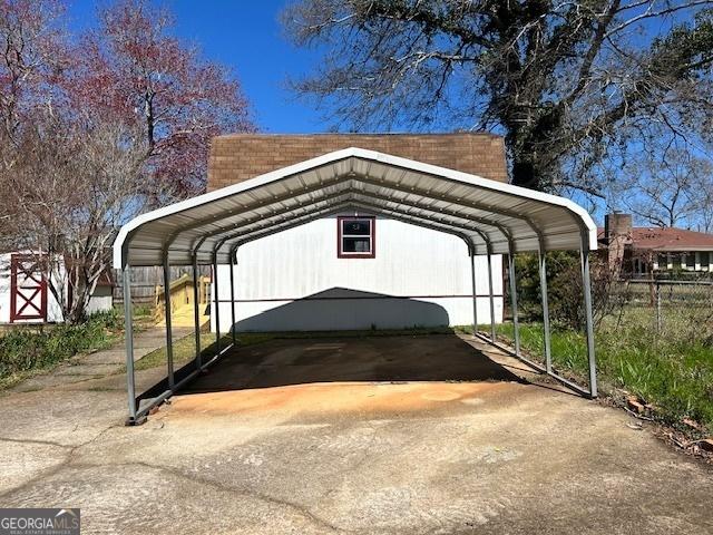 view of car parking featuring a carport, driveway, and fence