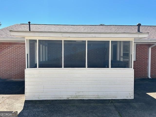 view of side of property featuring brick siding and a sunroom