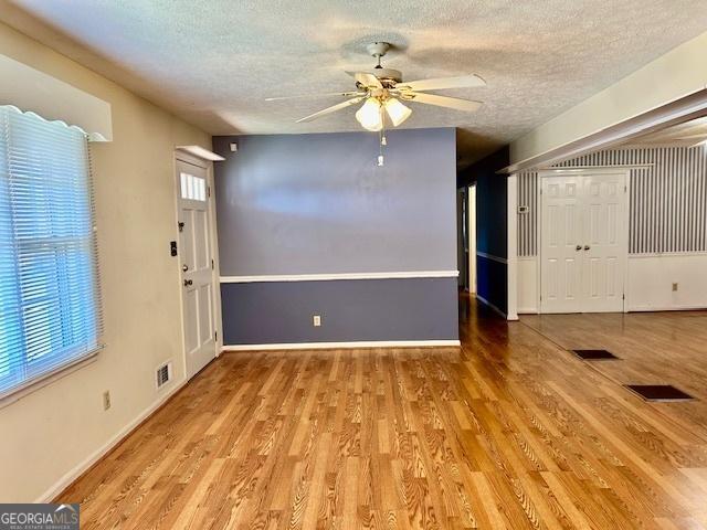 entryway featuring visible vents, baseboards, wood finished floors, a textured ceiling, and a ceiling fan