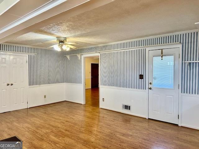 foyer featuring visible vents, wallpapered walls, and wood finished floors