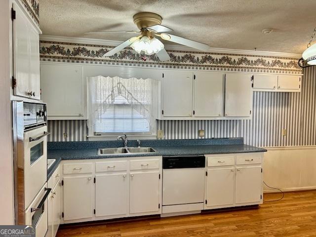 kitchen featuring dishwasher, dark countertops, white cabinets, and a sink