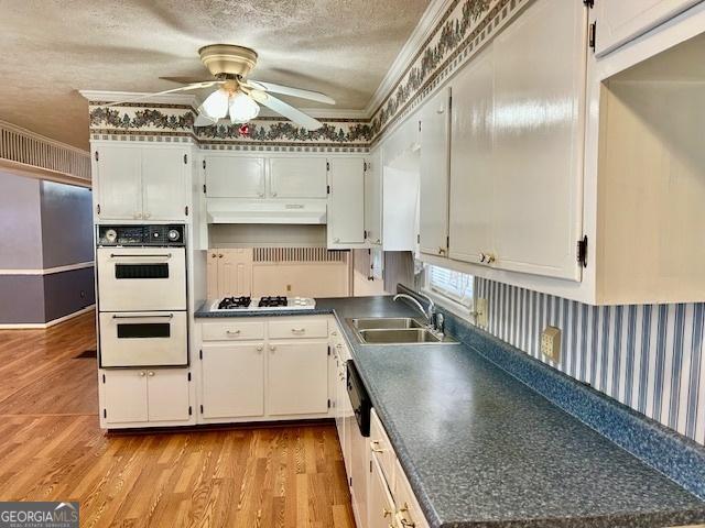 kitchen with a ceiling fan, a sink, under cabinet range hood, a textured ceiling, and white appliances