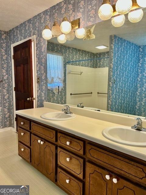 full bathroom with curtained shower, wallpapered walls, and a sink