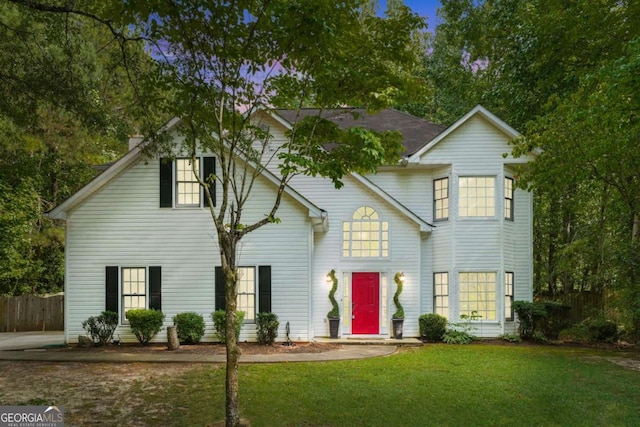 traditional-style home with a front yard and fence