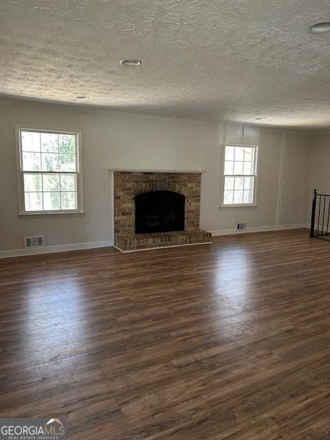 unfurnished living room with visible vents, a fireplace, dark wood-style flooring, and baseboards