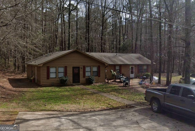 ranch-style house with a wooded view and a front lawn