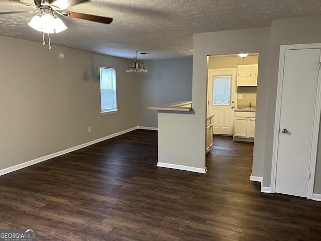 unfurnished room featuring a sink, a textured ceiling, baseboards, and dark wood-style flooring