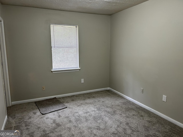 carpeted spare room featuring a textured ceiling and baseboards