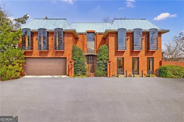 view of front facade featuring brick siding, an attached garage, metal roof, and a standing seam roof