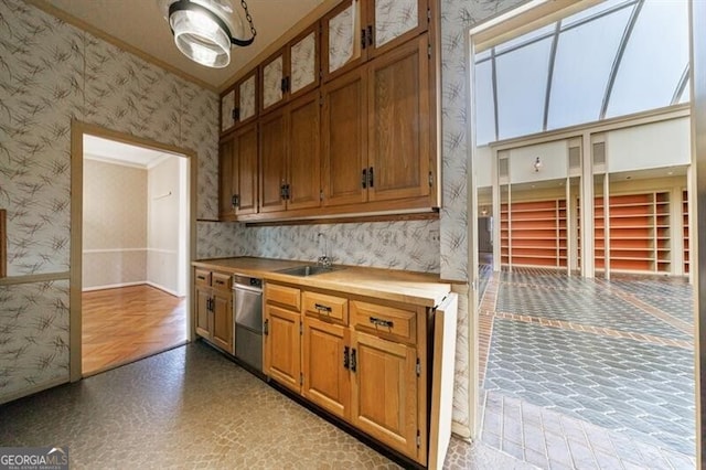 kitchen featuring a sink, wood counters, stainless steel dishwasher, brown cabinetry, and wallpapered walls