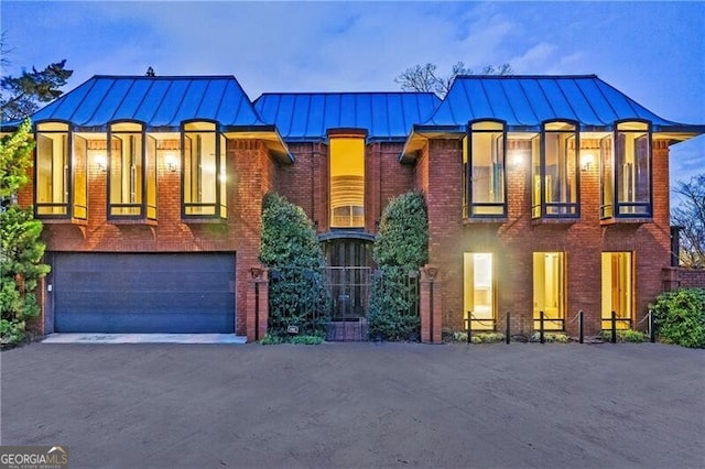 view of front of home with a garage, driveway, a standing seam roof, metal roof, and brick siding