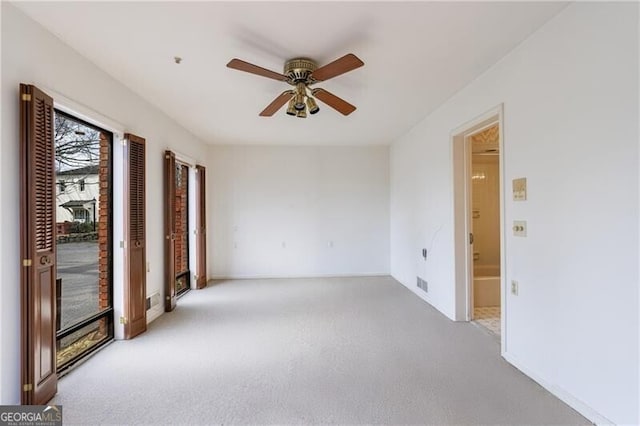 unfurnished room with visible vents, baseboards, light colored carpet, and ceiling fan