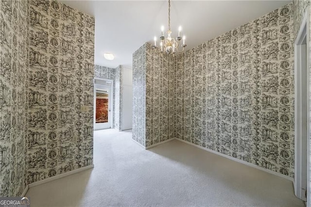 empty room featuring wallpapered walls, an inviting chandelier, carpet flooring, and baseboards