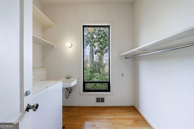 laundry room featuring washer / dryer, a healthy amount of sunlight, visible vents, and light wood-type flooring