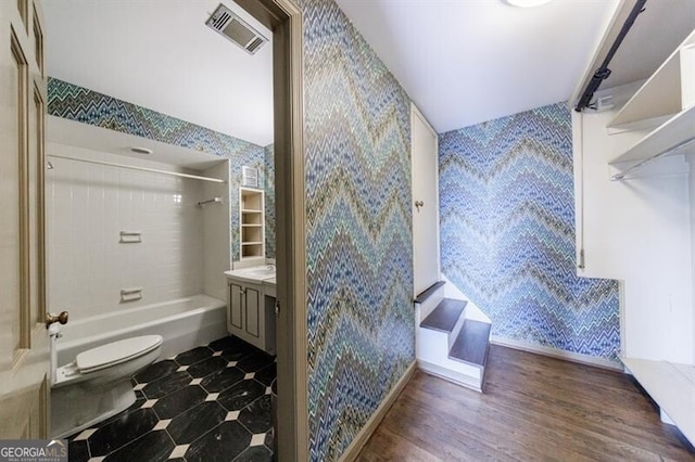 bathroom featuring visible vents, toilet, vanity, and shower / tub combination