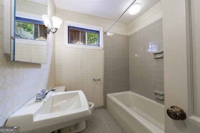 full bath with tile patterned floors, a sink,  shower combination, wallpapered walls, and baseboards