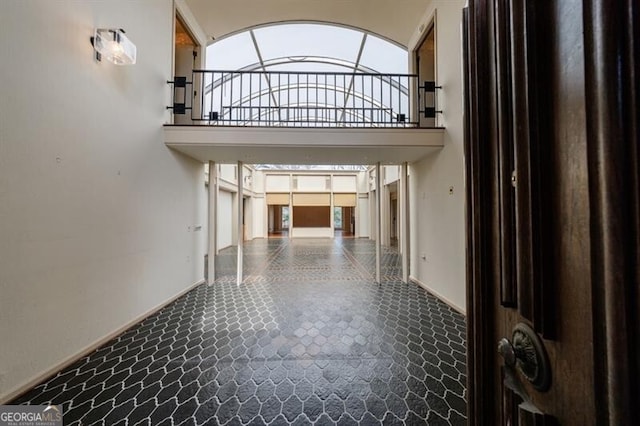 hall featuring a high ceiling and baseboards