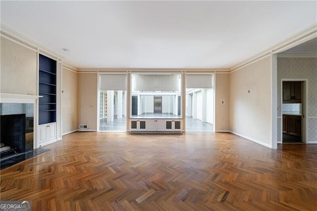 unfurnished living room featuring built in features, visible vents, baseboards, a premium fireplace, and ornamental molding