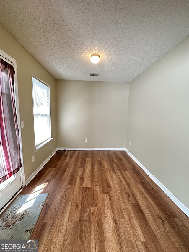 unfurnished room with visible vents, baseboards, and wood finished floors