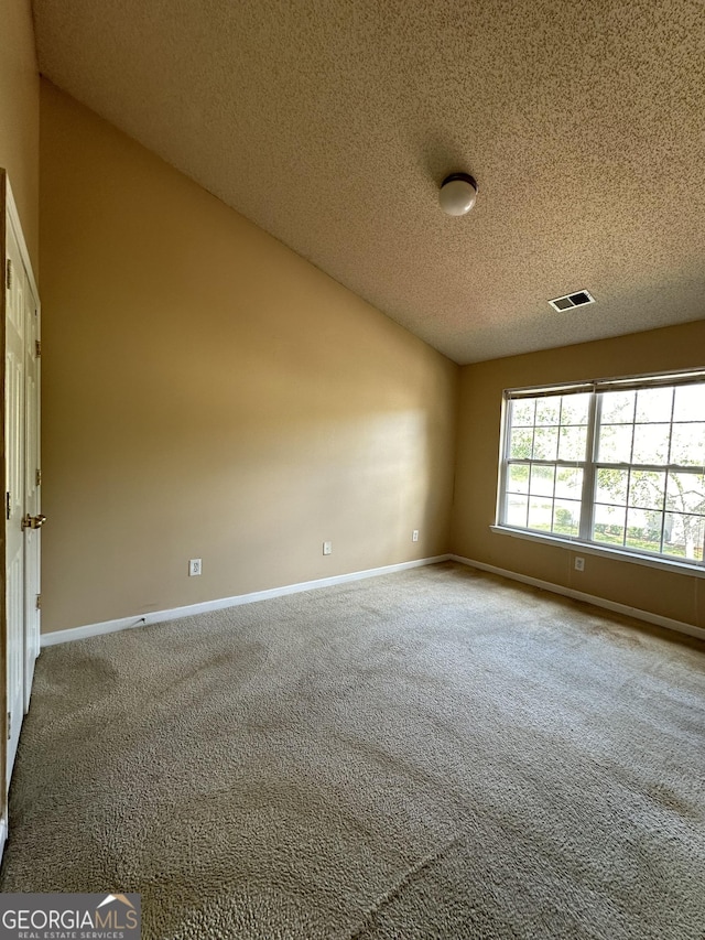 carpeted spare room featuring lofted ceiling, baseboards, visible vents, and a textured ceiling