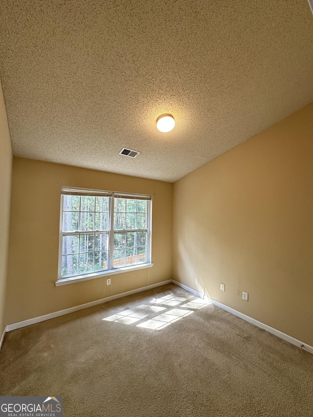 empty room featuring visible vents, a textured ceiling, baseboards, and carpet floors