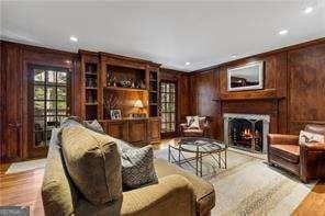 living room featuring wood finished floors, a lit fireplace, wood walls, and crown molding