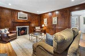 living room featuring a warm lit fireplace, recessed lighting, light wood-style floors, and wood walls