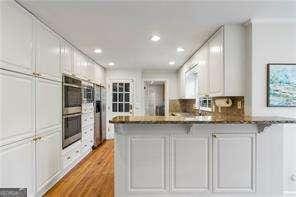 kitchen featuring white cabinetry, recessed lighting, double oven, a peninsula, and light wood finished floors