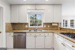 kitchen with a sink, decorative backsplash, stainless steel dishwasher, and white cabinets