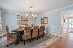 dining area featuring wood finished floors, a notable chandelier, and ornamental molding