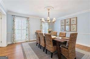 dining room featuring wood finished floors, an inviting chandelier, and ornamental molding