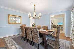 dining space with a chandelier, wood finished floors, baseboards, and ornamental molding