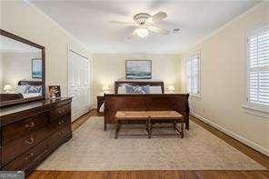 bedroom featuring crown molding, light wood-style flooring, and a ceiling fan