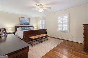 bedroom featuring baseboards, wood finished floors, a ceiling fan, and ornamental molding