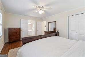 bedroom featuring dark wood finished floors, a ceiling fan, a closet, and ornamental molding