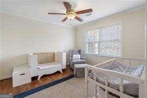 bedroom with wood finished floors and ornamental molding