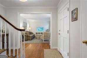 hall with crown molding, stairway, and wood finished floors