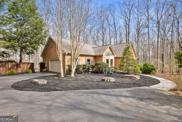 view of front of home with brick siding, fence, roof with shingles, a garage, and driveway