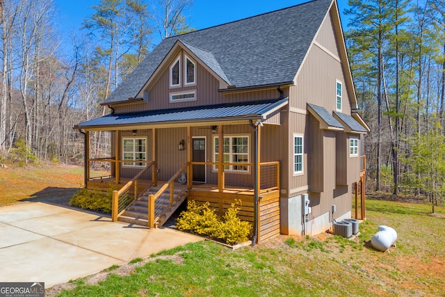 chalet / cabin featuring a shingled roof, ceiling fan, a front lawn, a porch, and metal roof