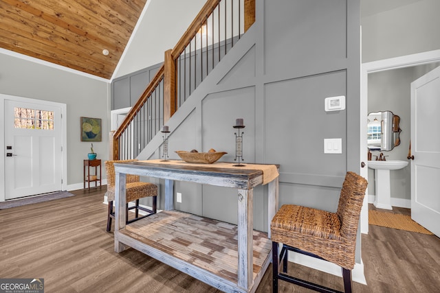 foyer featuring baseboards, high vaulted ceiling, wood finished floors, and stairs