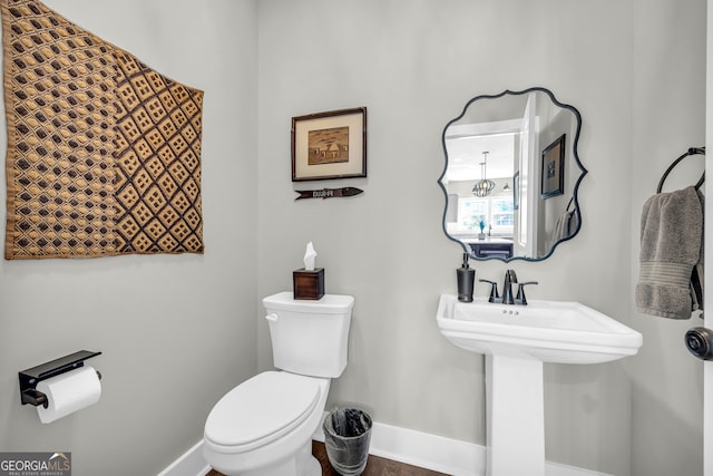 half bath featuring toilet, baseboards, and a sink